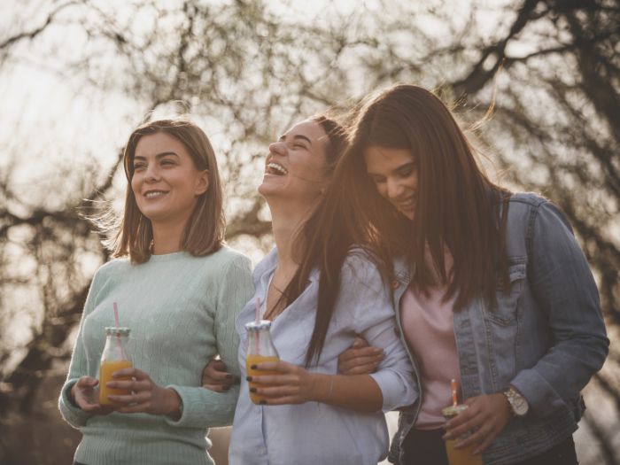 Three women drinking juice in a park